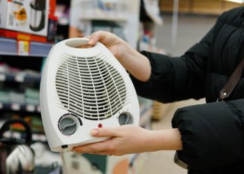 Woman customer choosing electric fan heater at construction supply store. Close up.