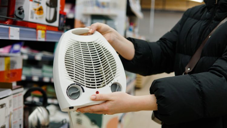 Woman customer choosing electric fan heater at construction supply store. Close up.