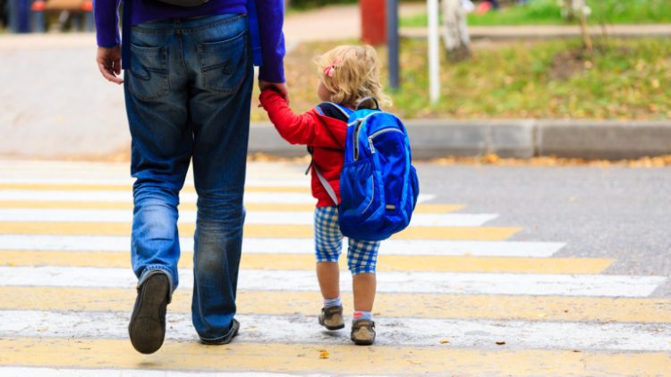 father walking little daughter with backpack to school or daycare