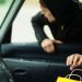 Transportation, crime and ownership concept - thief stealing shopping bag from the car